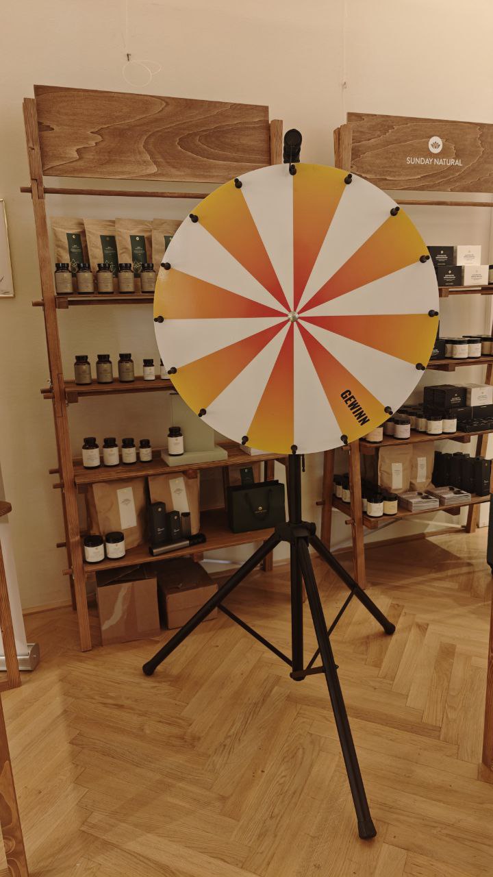 Glücksrad mit orange-gelbem Farbverlauf und weißen Segmenten in einem Ladengeschäft aufgestellt